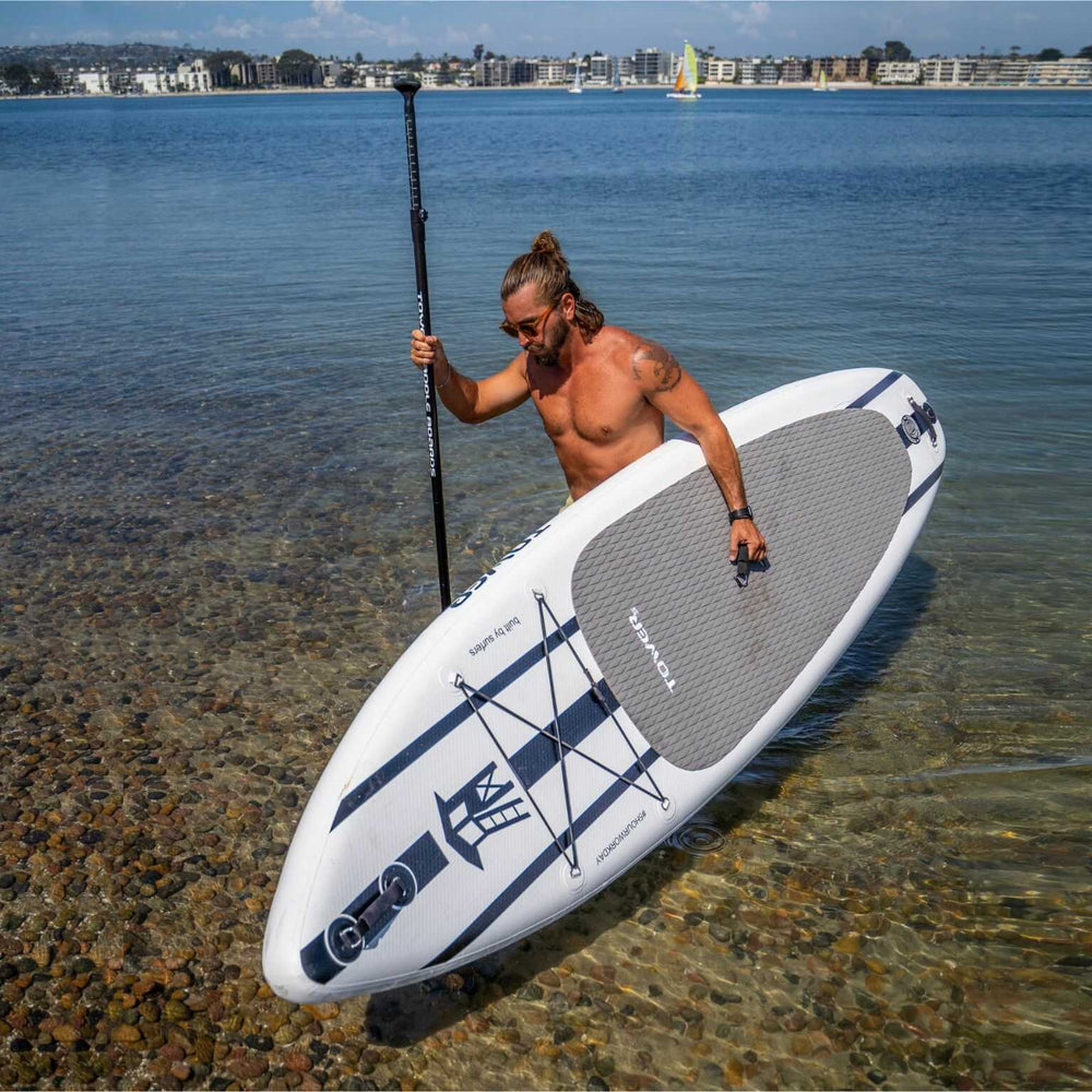 Man getting out of the water with a Tower S-Class paddle board under his arm